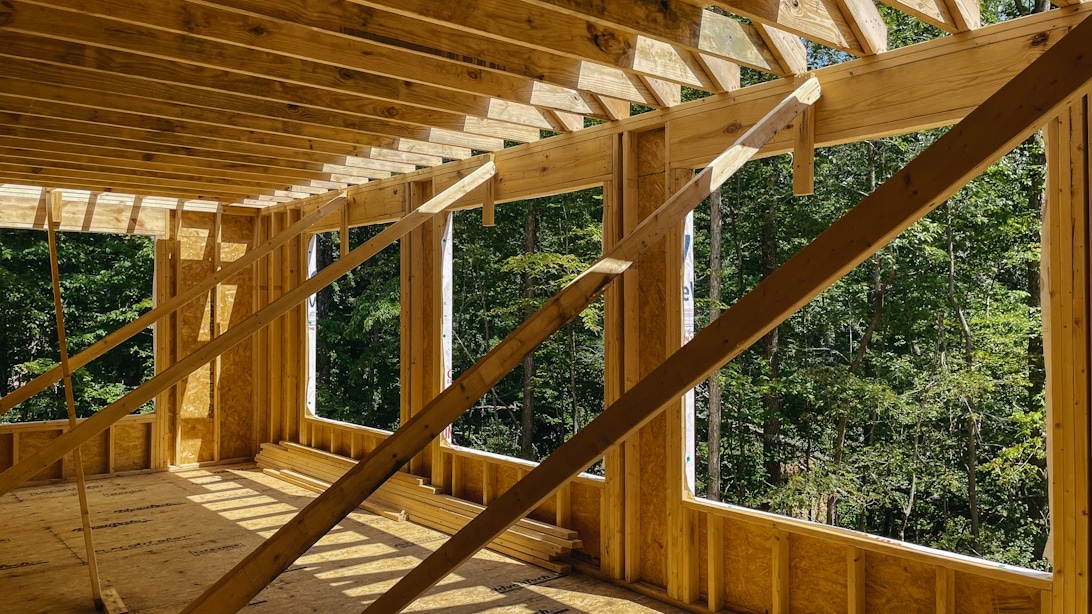 Eine Holzrahmenkonstruktion eines Gebäudes im Wald, die nachhaltige Baupraktiken mit Holz veranschaulicht.
